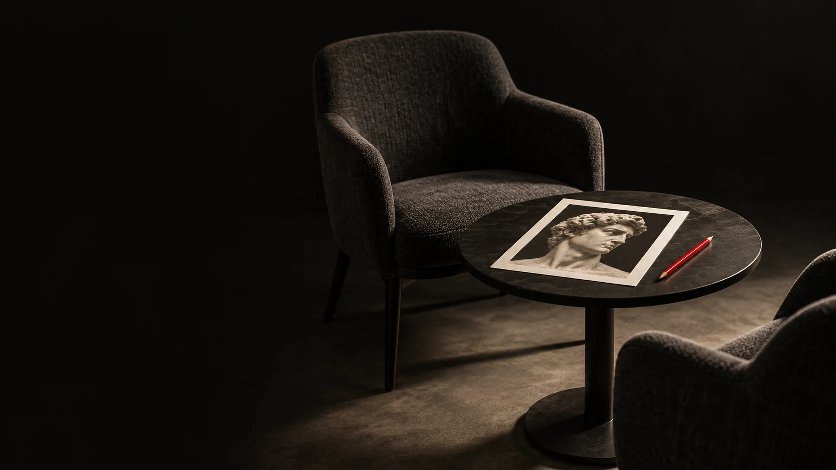Sillones junto a una mesa con una lámina del David y un lápiz rojo